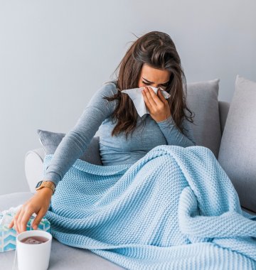 Frau liegt mit Schnupfen im Bett