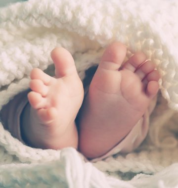 Babyfüße schauen aus eine Bettdecke raus