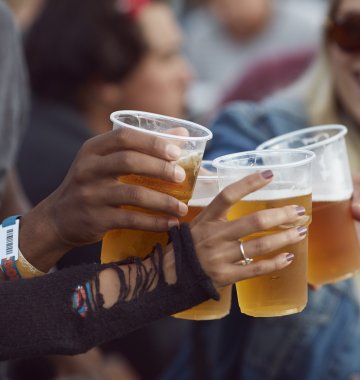 Junge Leute, die mit Bier in Plastikbechern anstoßen
