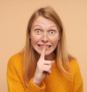 Frau mit gestrecktem Zeigefinger vor dem Mund