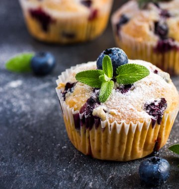Ein Blaubeermuffin ist mit Blaubeeren und Minzblättern dekoriert