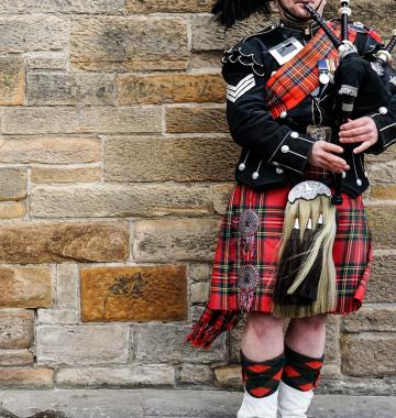 Mann mit typisch schottischer Kleidung und Dudelsack
