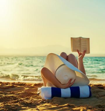 Frau liest Buch am Meer