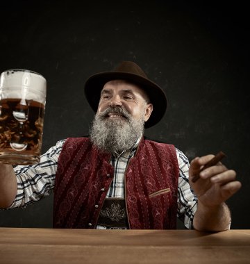Mann in traditioneller Kleidung hebt eine Maß Bier