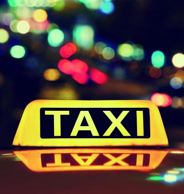 Taxischild auf einem Taxi bei Nacht