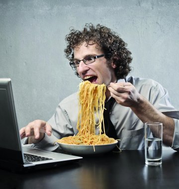 Ein Mann sitzt vor dem Laptop und isst