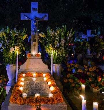 Ein Grab mit Kerzen und Dekoration unter einem Kreuz