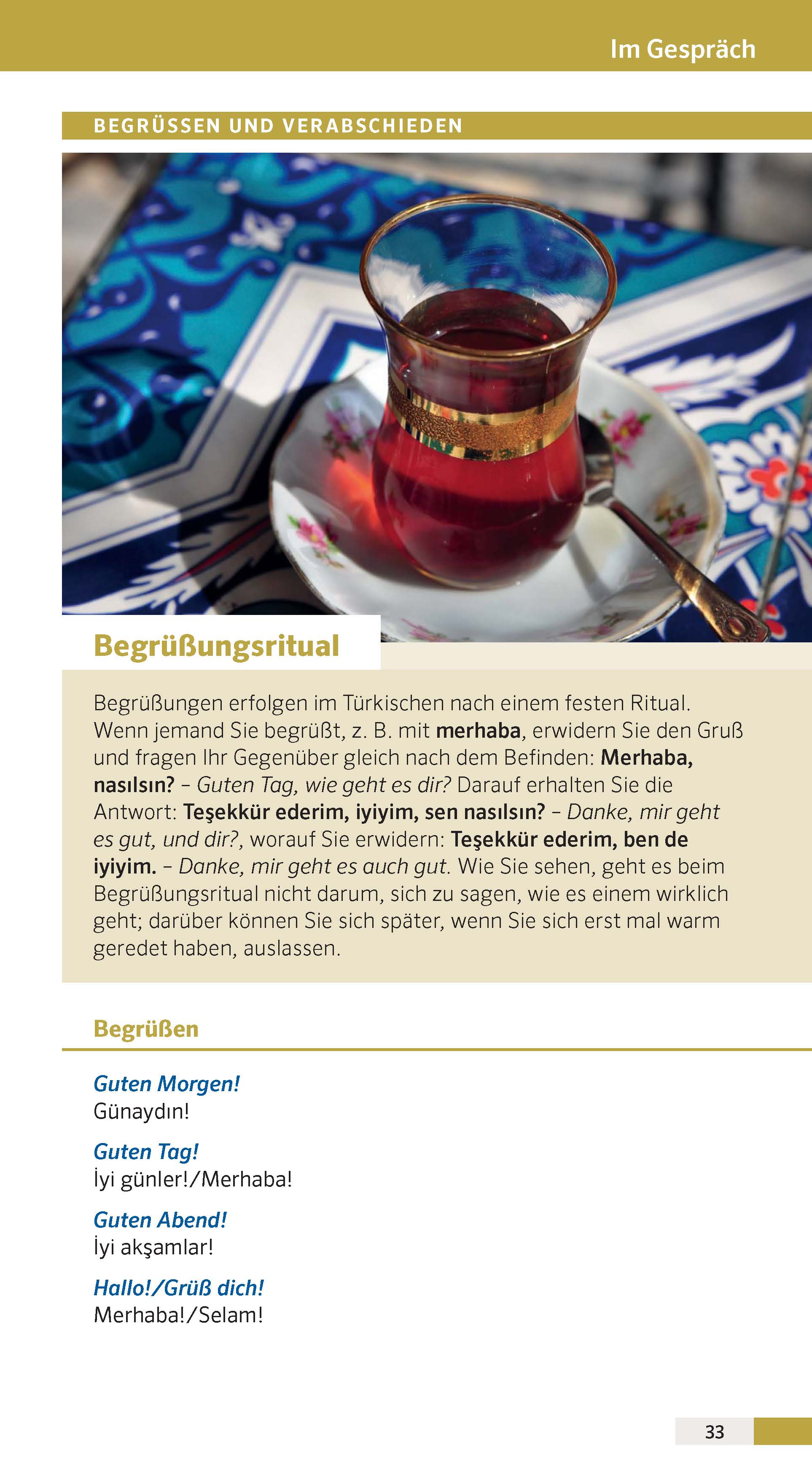 Ein Glas türkischer Tee mit einem Löffel auf einer Untertasse steht auf einem Tisch neben einer Seite mit einem deutschen Text, der türkische Grüße erklärt.