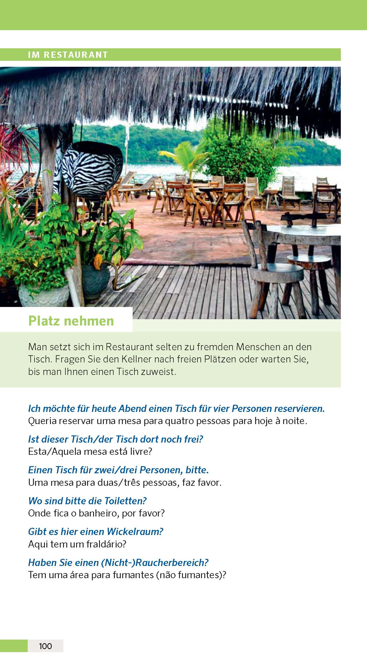 Außenbereich des Restaurants mit leeren Tischen und Stühlen unter einem Strohdach, umgeben von Grün, mit Holzboden und Stufen, die nach unten führen.